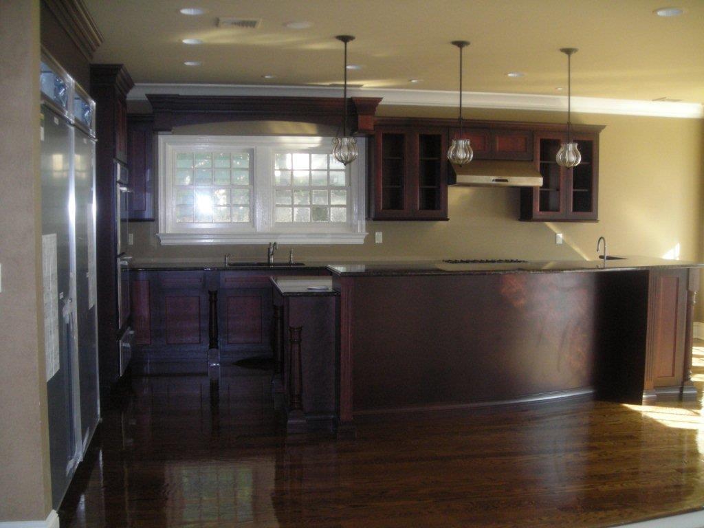 A kitchen with dark wood cabinets and wooden floors.