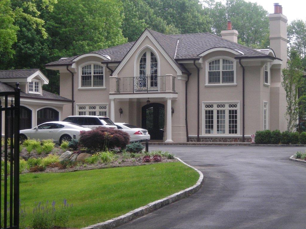 A large house with a driveway and car parked in front.