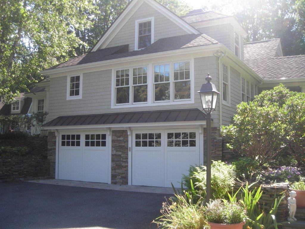 A house with two garage doors and a stone roof.