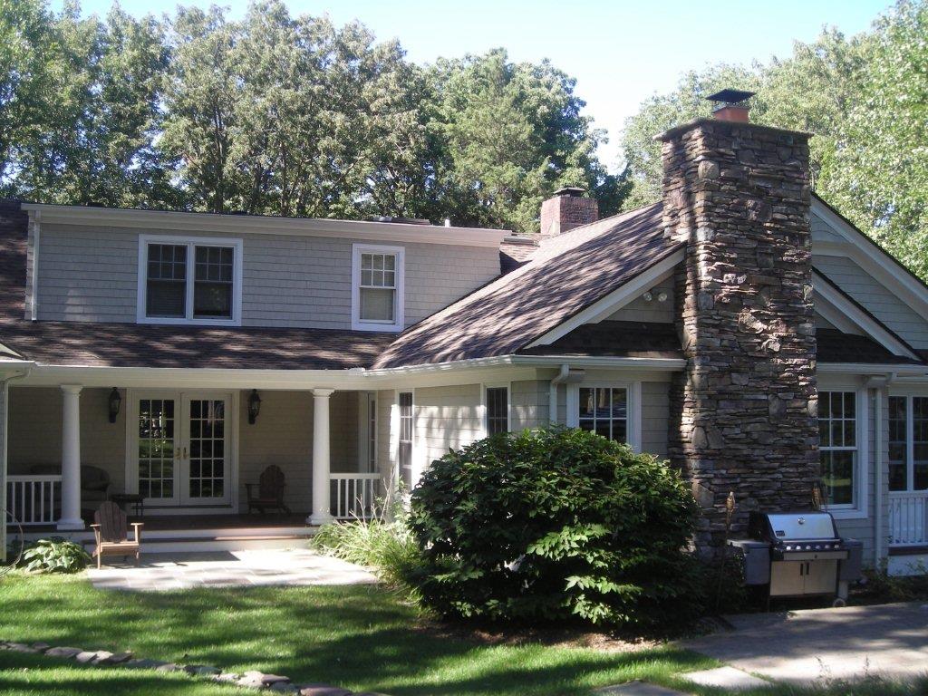 A house with a large stone chimney in the middle of it.