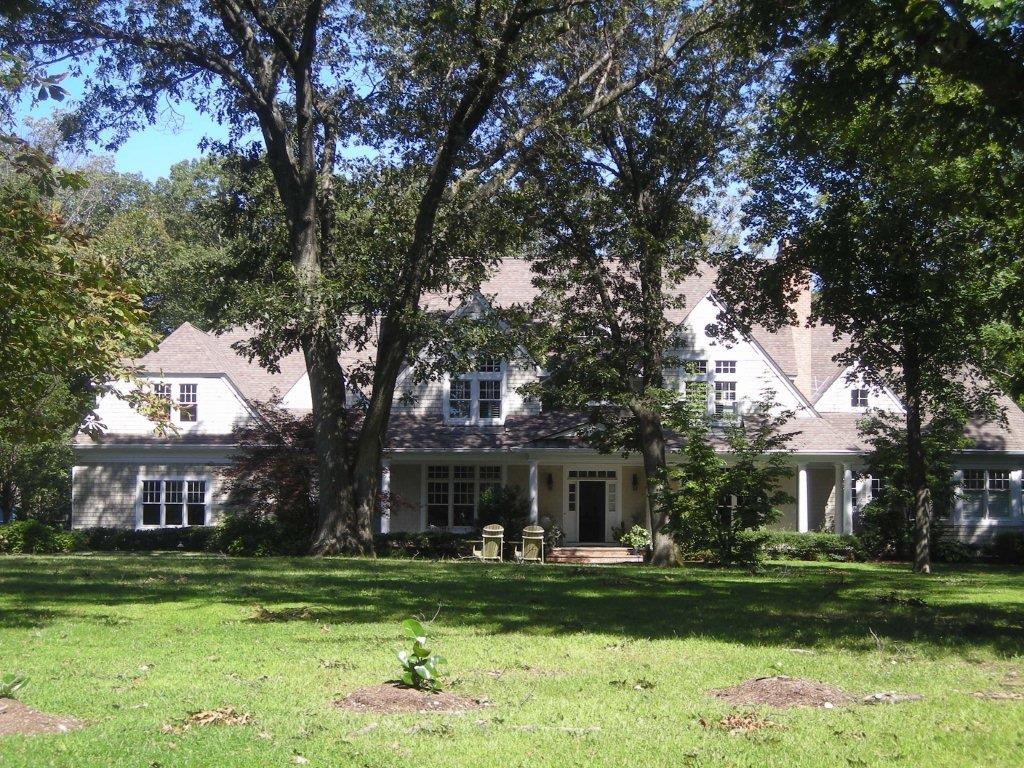 A large white house with trees in the background.