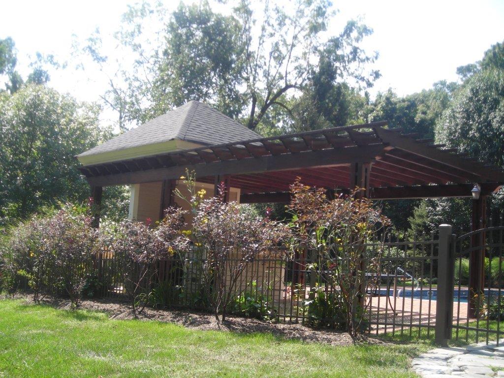 A gazebo with a fence and trees in the background.