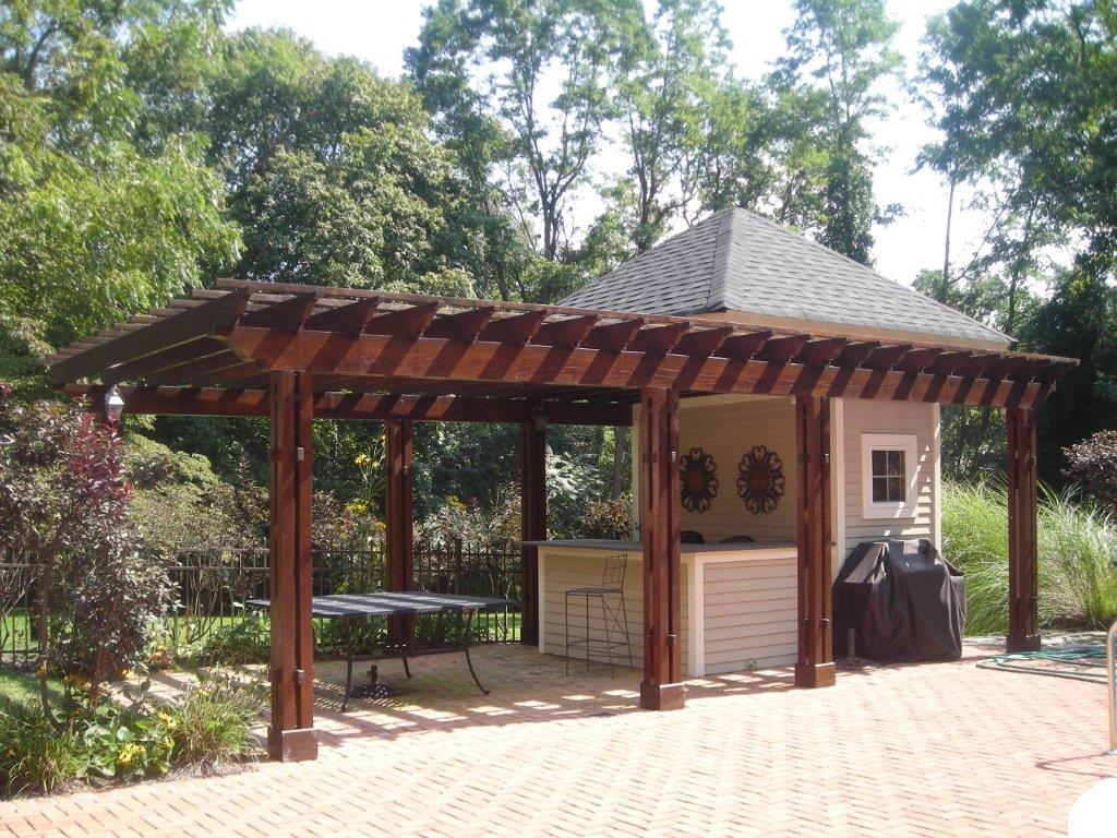 A large outdoor grill sitting under a wooden structure.
