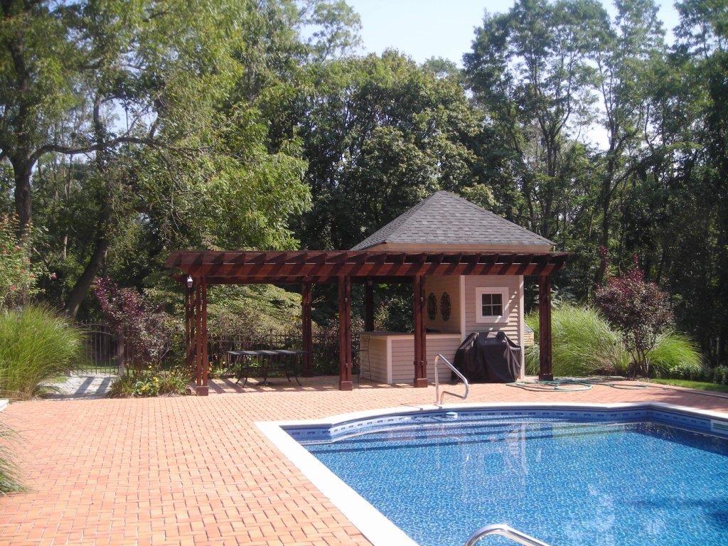 A pool with an outdoor grill and gazebo.