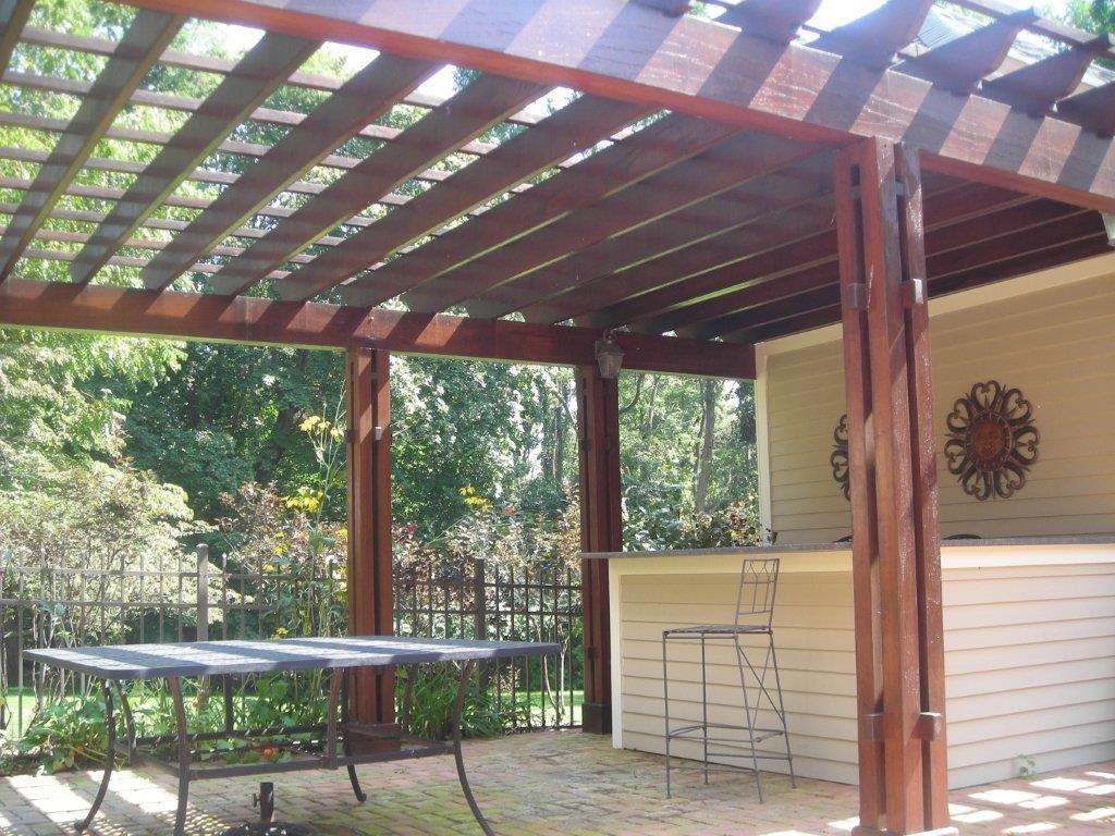 A wooden pergola with a table and chairs