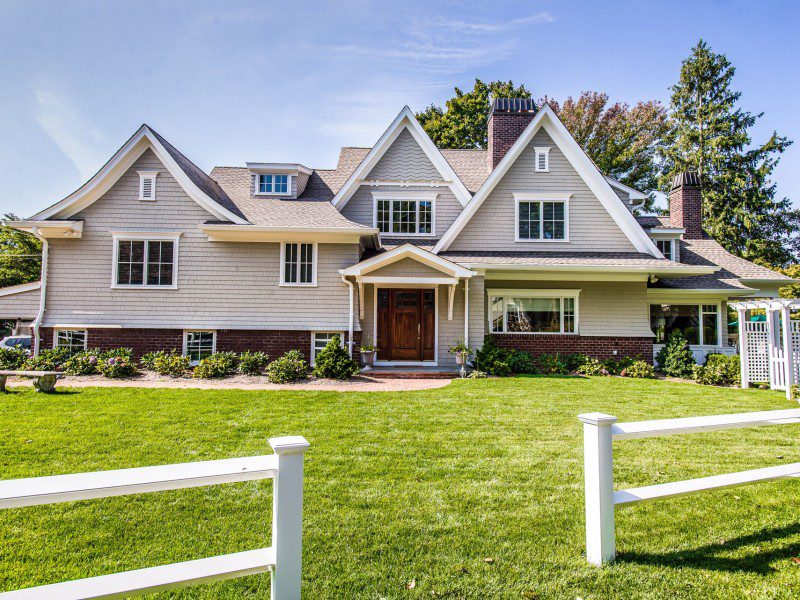 A large white house with a green lawn and trees.