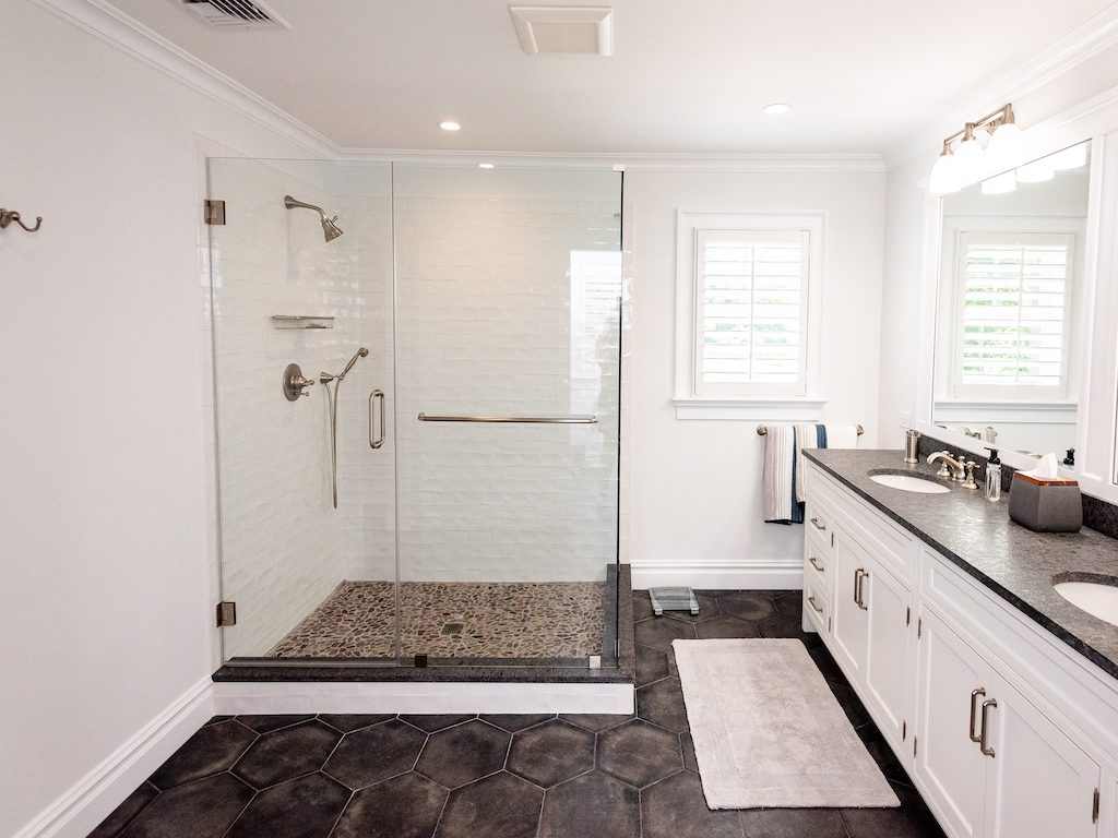 A bathroom with a shower, sink and mirror.