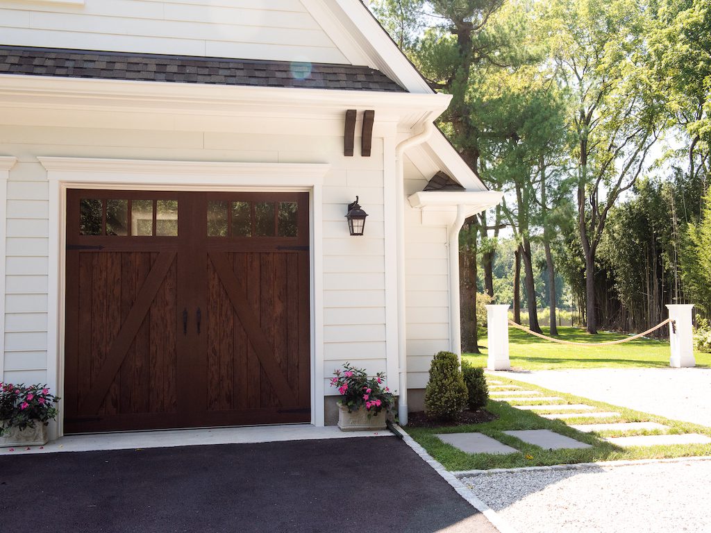A white garage with a wooden door and a flower pot.