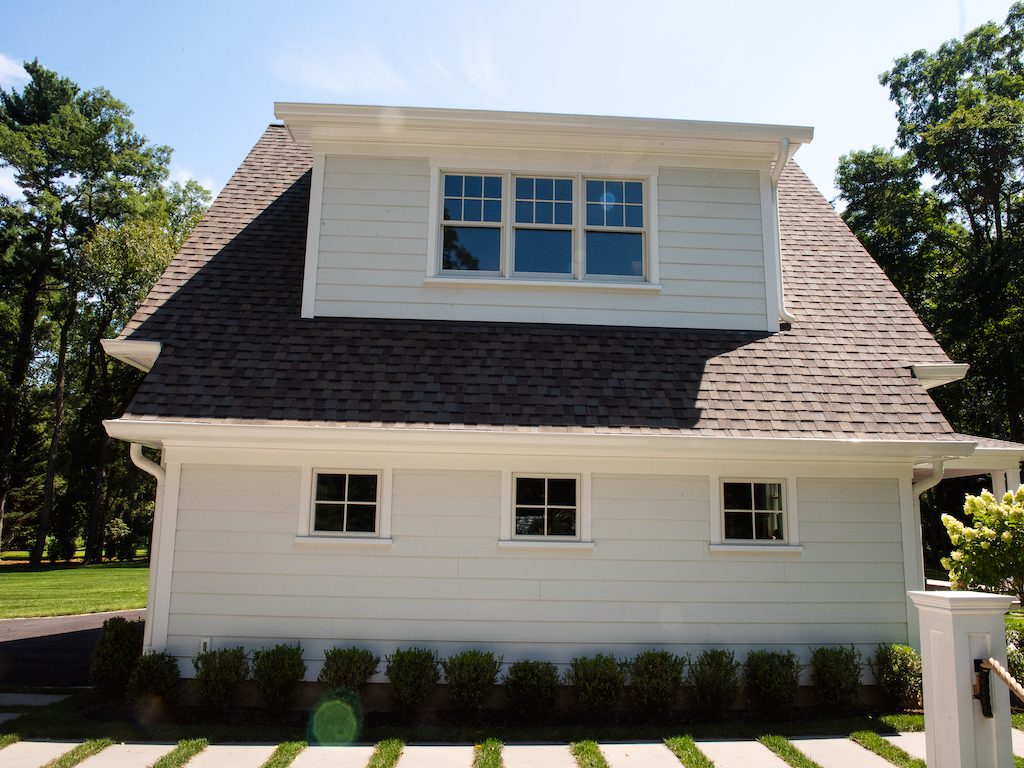 A white house with a large window and a green lawn.